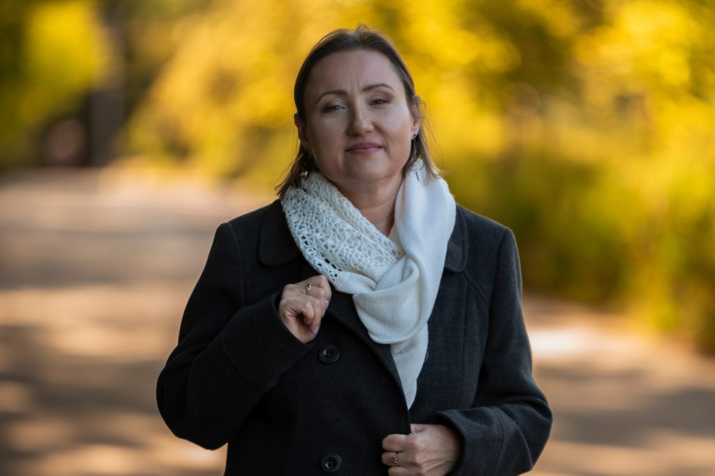 Młoda kobieta w ciemnym płaszczu i białym szalokominie na szyi