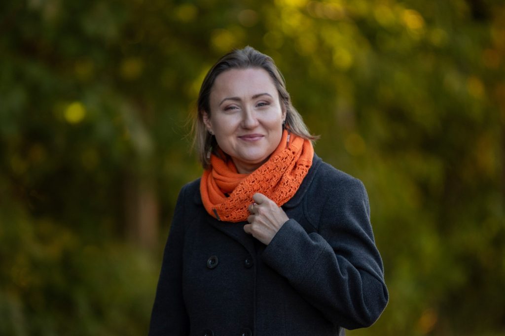 młoda kobieta w ciemnym ubraniu i pomarańczowym szalokominie